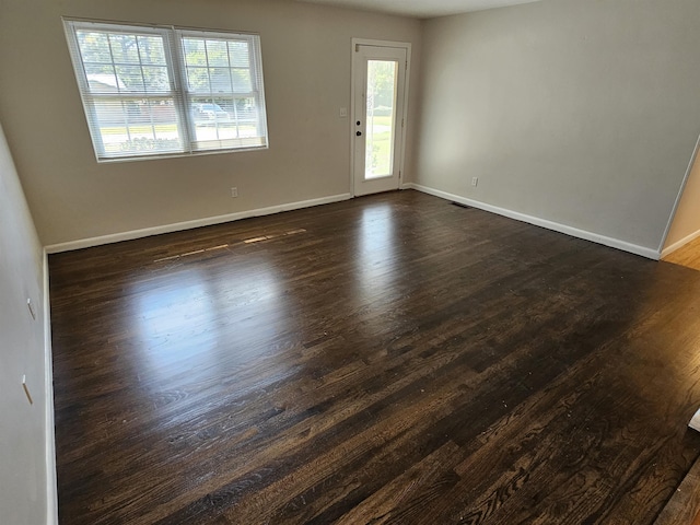 spare room featuring dark wood-style floors and baseboards