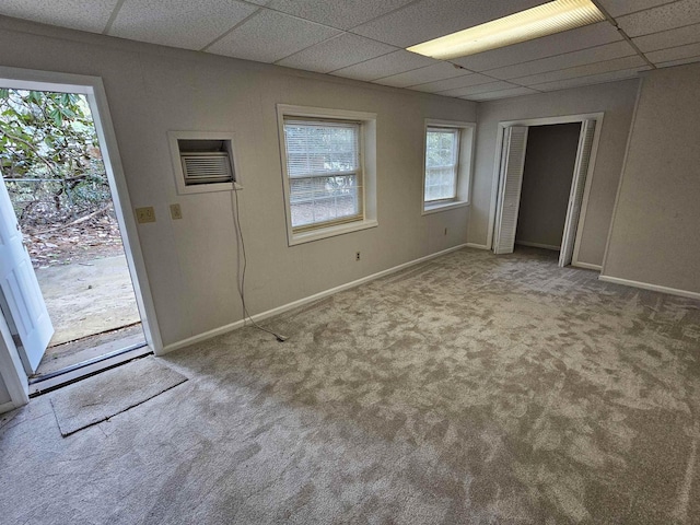 carpeted empty room with baseboards and a drop ceiling