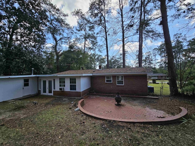 rear view of house with french doors, brick siding, a patio, and fence