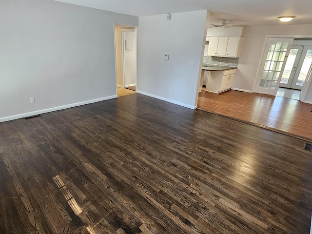 unfurnished living room featuring a ceiling fan, dark wood-style flooring, visible vents, and baseboards