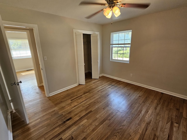 unfurnished bedroom with dark wood-style floors, a closet, baseboards, and a ceiling fan