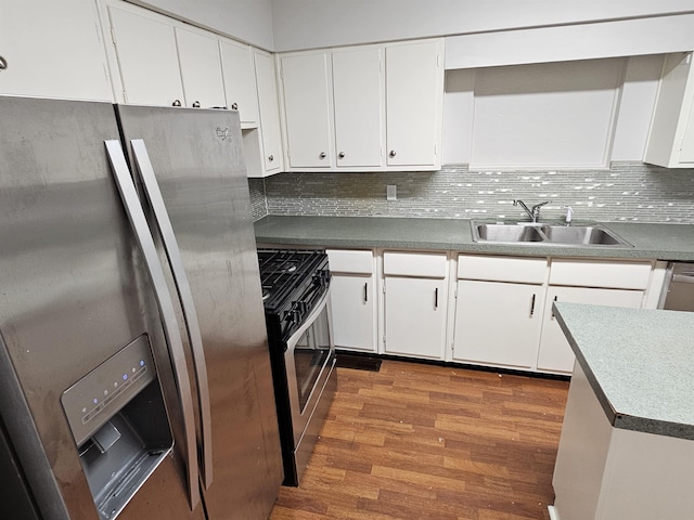 kitchen featuring decorative backsplash, appliances with stainless steel finishes, white cabinetry, a sink, and wood finished floors