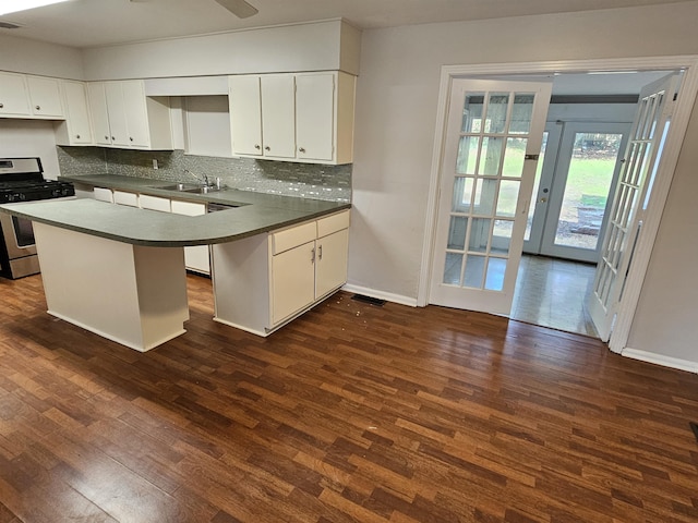 kitchen featuring stainless steel gas range oven, a sink, dark wood finished floors, and white cabinets