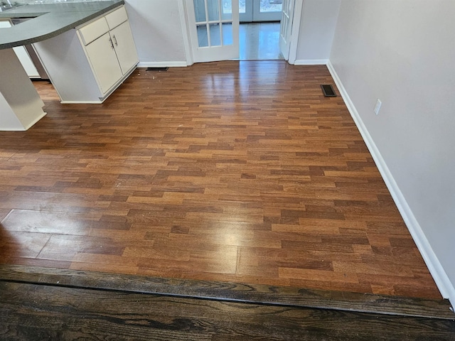 interior space with dark wood-style flooring, visible vents, and baseboards