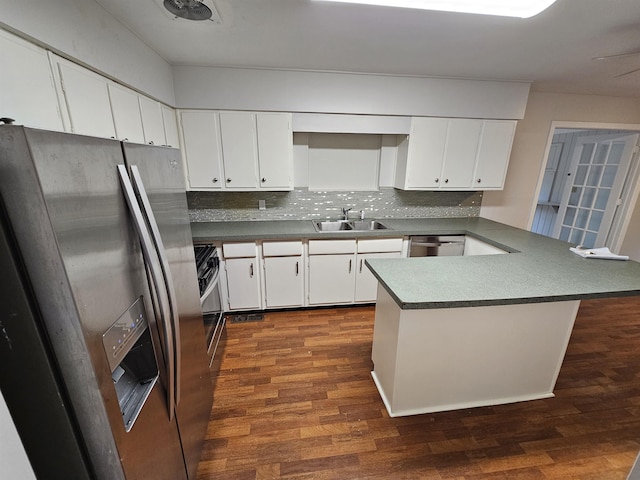 kitchen with stainless steel appliances, tasteful backsplash, a sink, and dark wood finished floors