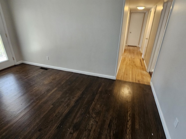 unfurnished room with visible vents, baseboards, and wood finished floors