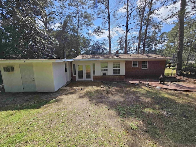 back of house featuring brick siding, a fire pit, and french doors