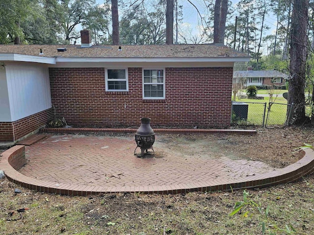 exterior space with brick siding, a chimney, a gate, a patio area, and fence