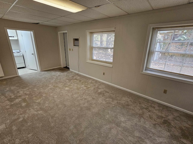 carpeted empty room featuring a paneled ceiling and baseboards