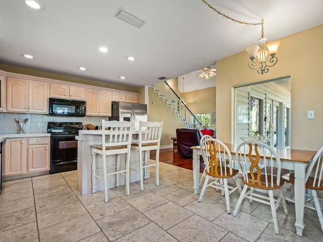 kitchen featuring a notable chandelier, a center island, black appliances, decorative backsplash, and decorative light fixtures