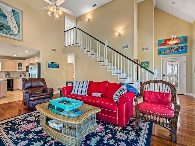 living room with ceiling fan, wood-type flooring, and a high ceiling