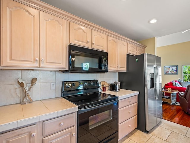 kitchen featuring light brown cabinets, backsplash, black appliances, light tile patterned floors, and tile counters