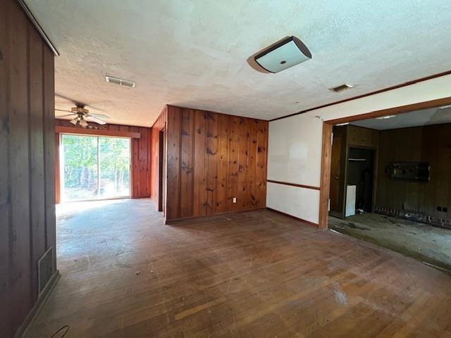 spare room featuring ceiling fan, a textured ceiling, and wooden walls