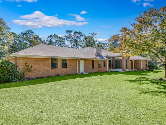 rear view of house featuring a sunroom and a lawn