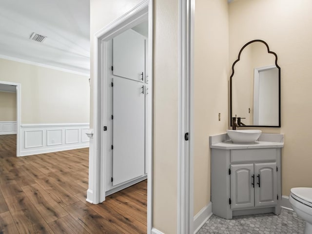 bathroom with toilet, vanity, hardwood / wood-style floors, and ornamental molding