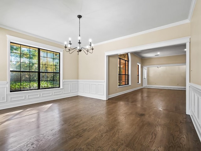 empty room with an inviting chandelier, dark hardwood / wood-style flooring, and ornamental molding