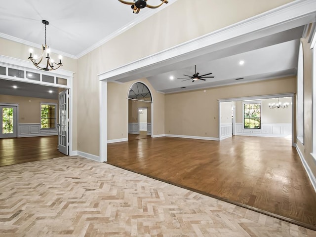 interior space with a wealth of natural light, ceiling fan with notable chandelier, ornamental molding, and light hardwood / wood-style flooring