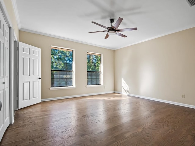 empty room with ornamental molding, dark wood-type flooring, and ceiling fan