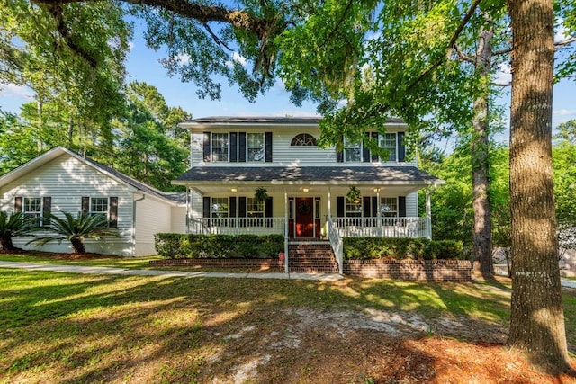 colonial house featuring covered porch and a front yard