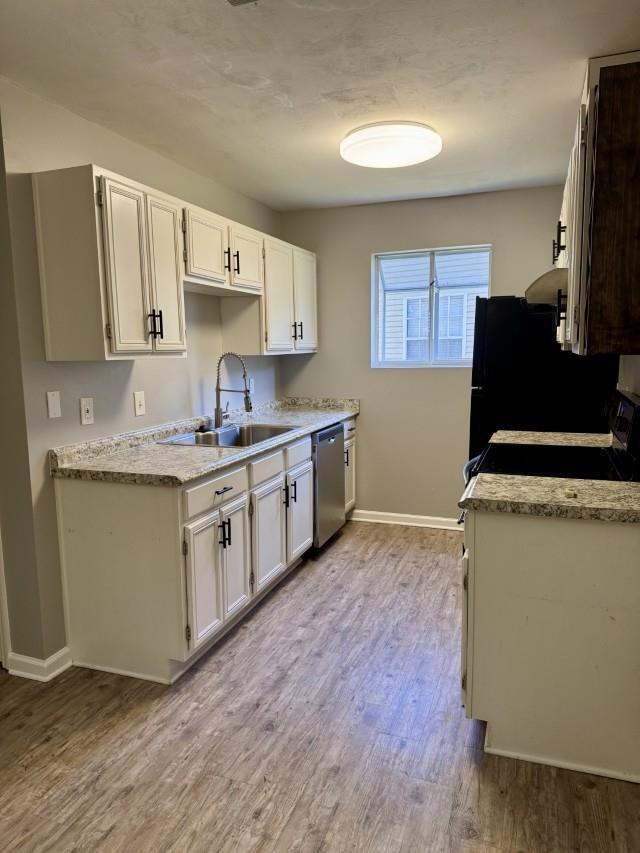 kitchen with light hardwood / wood-style flooring, white cabinets, black appliances, and sink