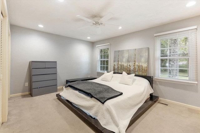 carpeted bedroom featuring multiple windows and ceiling fan