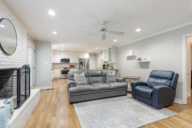 living room featuring ornamental molding, a brick fireplace, ceiling fan, and light hardwood / wood-style flooring