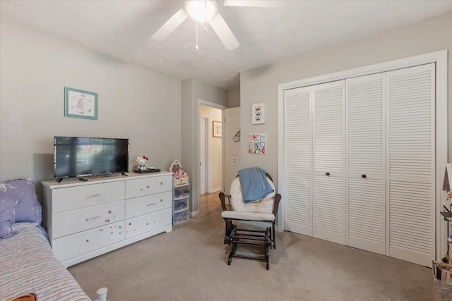 bedroom with light colored carpet, ceiling fan, and a closet