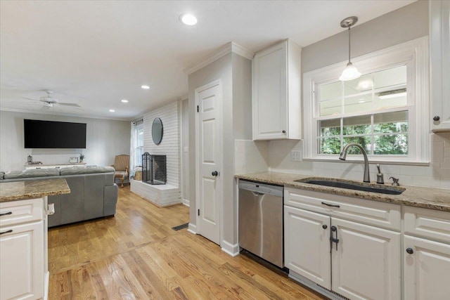 kitchen featuring pendant lighting, white cabinetry, sink, stainless steel dishwasher, and light stone countertops