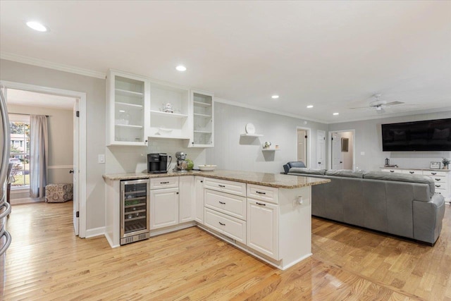 kitchen featuring wine cooler, light stone counters, white cabinetry, and light hardwood / wood-style floors