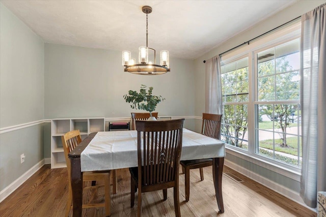 dining area with hardwood / wood-style flooring, plenty of natural light, and a notable chandelier