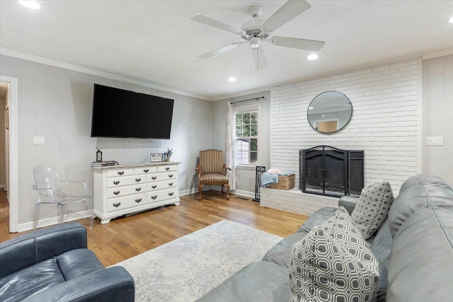 living room featuring crown molding, a brick fireplace, ceiling fan, and light hardwood / wood-style floors