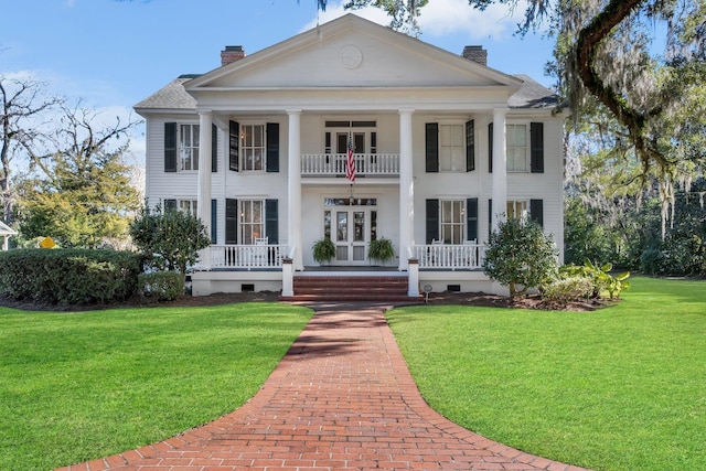 neoclassical / greek revival house with french doors, a balcony, and a front lawn