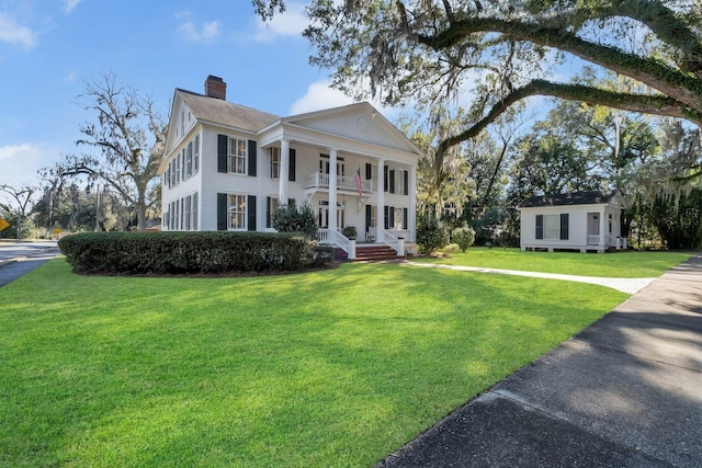 neoclassical / greek revival house featuring a balcony and a front yard