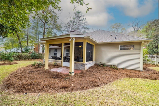 rear view of house with a shingled roof, a sunroom, a yard, and fence