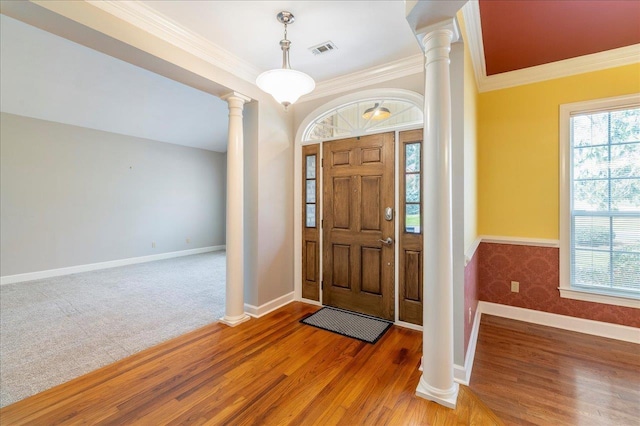 carpeted entrance foyer with plenty of natural light, wood finished floors, visible vents, and ornate columns