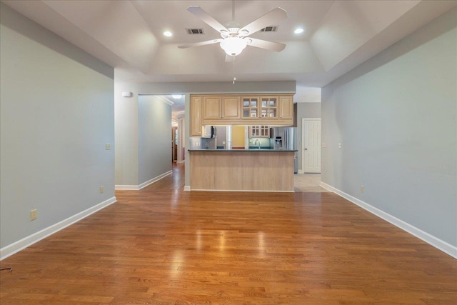 kitchen featuring light wood finished floors, dark countertops, stainless steel fridge, and visible vents