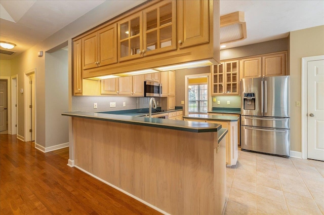 kitchen with stainless steel appliances, a peninsula, baseboards, decorative backsplash, and glass insert cabinets