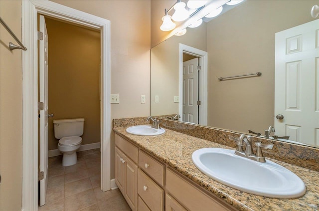 bathroom with double vanity, tile patterned flooring, a sink, and toilet