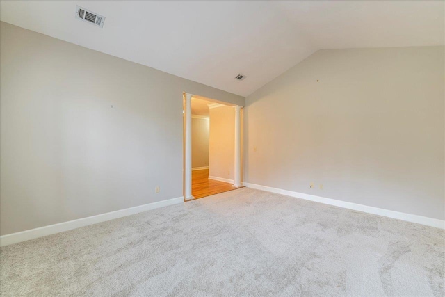 carpeted spare room featuring lofted ceiling, visible vents, and baseboards