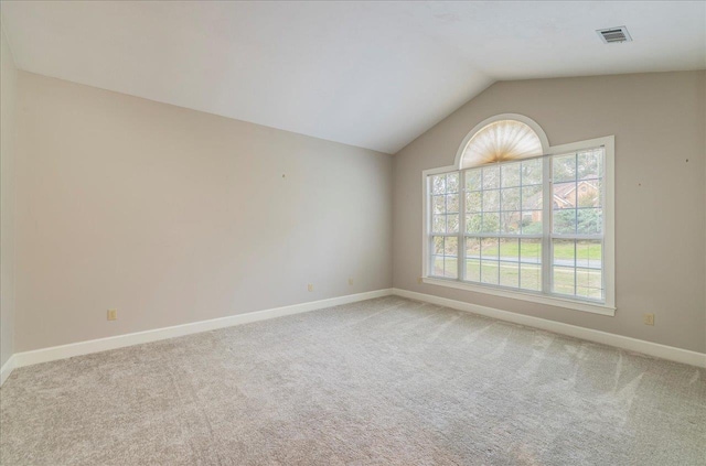 spare room featuring carpet floors, baseboards, visible vents, and lofted ceiling