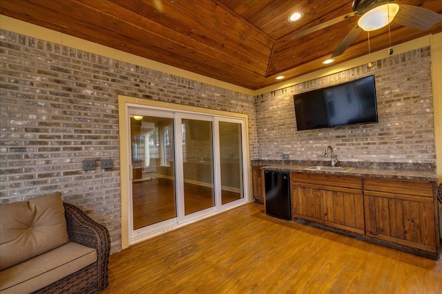 bar featuring brick wall, wood finished floors, a sink, wood ceiling, and dishwasher