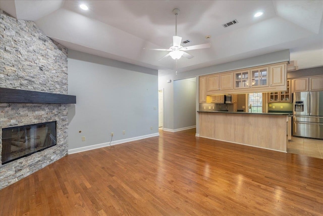 kitchen with dark countertops, light wood-style flooring, a fireplace, and stainless steel refrigerator with ice dispenser