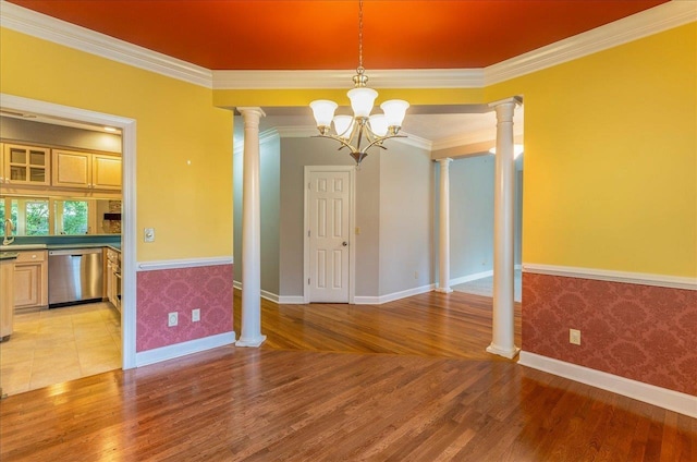 unfurnished dining area with a notable chandelier, ornamental molding, decorative columns, and light wood-style floors