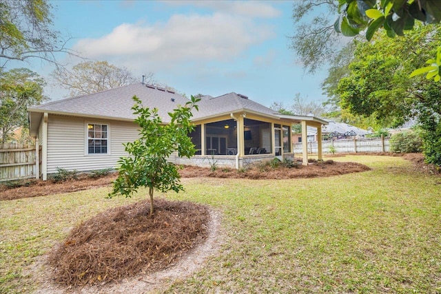 rear view of house with a sunroom, a shingled roof, fence, and a yard