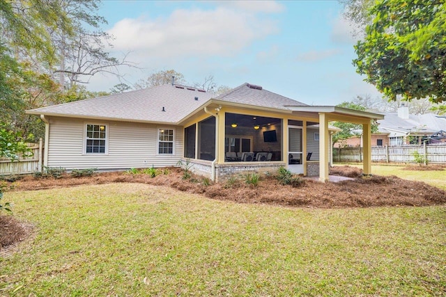 back of house featuring a yard, roof with shingles, fence, and a sunroom