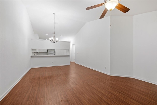 unfurnished living room with ceiling fan with notable chandelier, hardwood / wood-style flooring, and vaulted ceiling