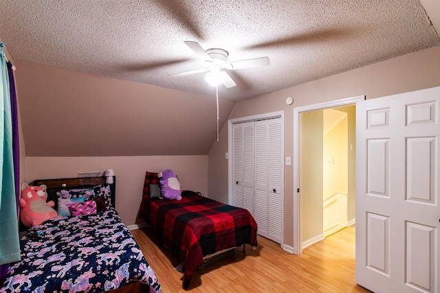 bedroom with vaulted ceiling, baseboards, a textured ceiling, light wood-style floors, and ceiling fan