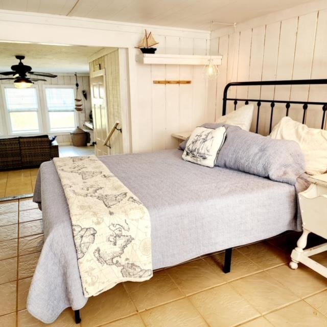 tiled bedroom with ornamental molding, wooden walls, and ceiling fan