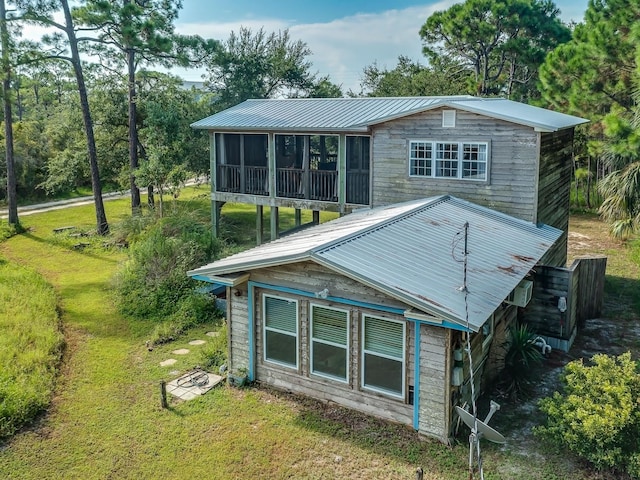 rear view of property featuring a sunroom and a yard