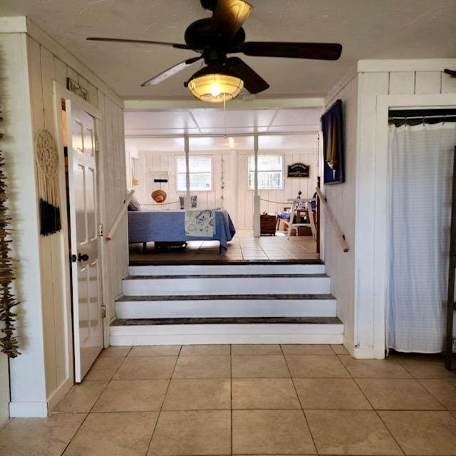 stairs with ornamental molding, tile patterned flooring, and ceiling fan